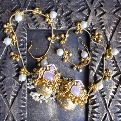 Gold and pearl jewelry set on a textured dark surface